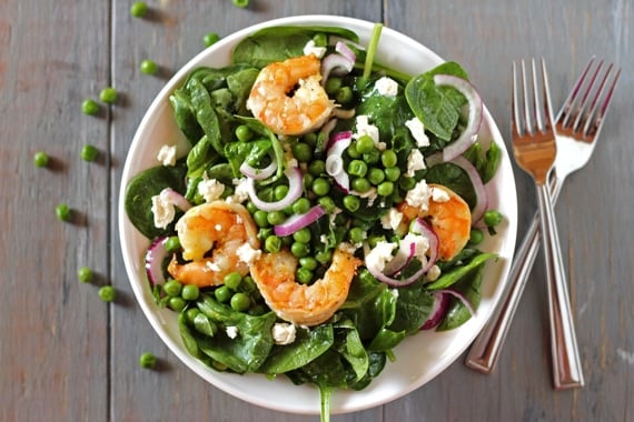 Shrimp and Spinach Salad served in a bowl and topped off with peas