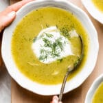 Person spooning a bowl of cream of zucchini soup