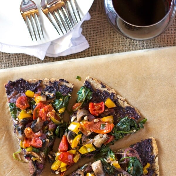 three slices of Spinach, Tomato and Olive Flatbread Pizza with wine on the side