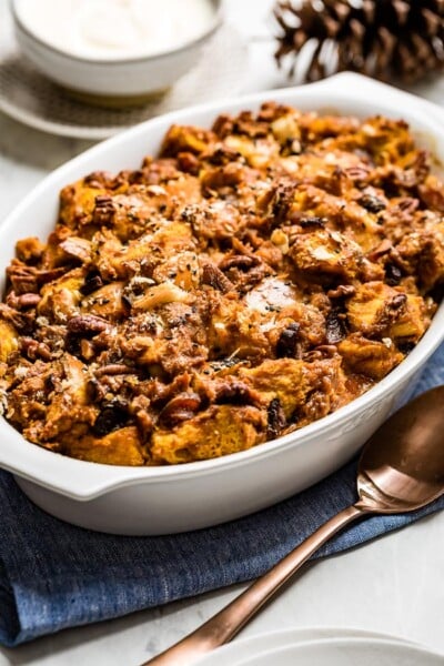 Pumpkin Bread Pudding in a casserole dish with a spoon on the side