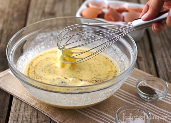 Mixture of Eggs, Artichoke, Tarragon, and Parmesan in a bowl with salt and pepper on a napkin with egg shells in the background