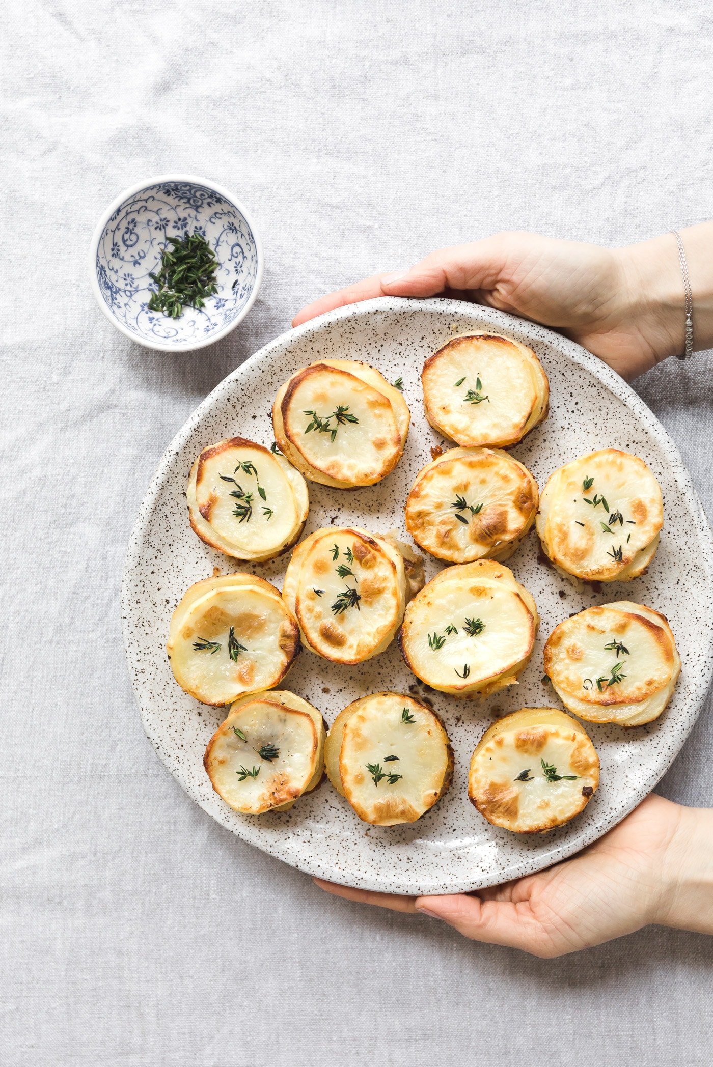 Muffin Tin Potatoes placed on a plate and being served by a woman