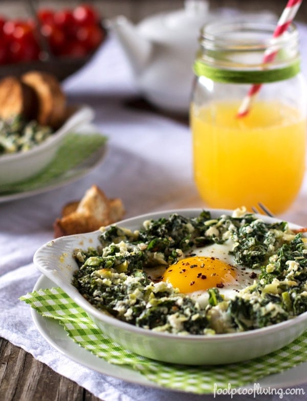 Bowl of Baked Eggs with Kale and Leeks with orange in the background