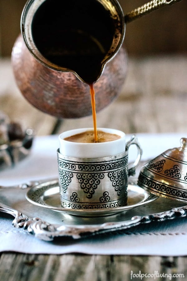 Turkish Coffee is being poured into the cup photographed from the front view