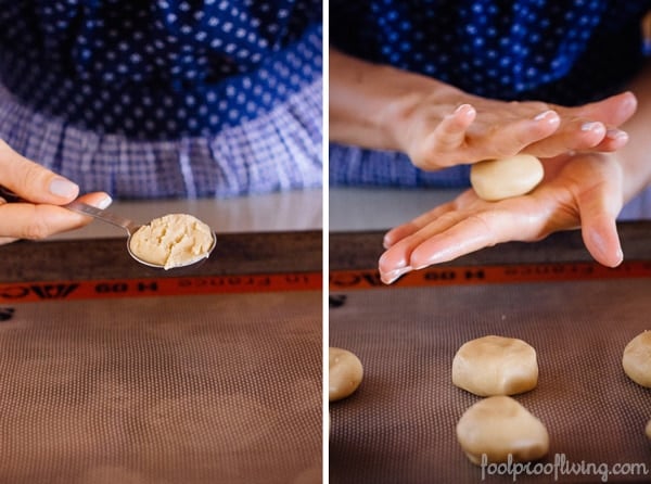 Person holding dough for Tahini Cookies with Pistachios with pressed tahini cookie dough on a sheet pan