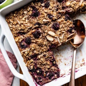 Baked Blackberry Oatmeal sliced in a baking dish with a spoon on the side.