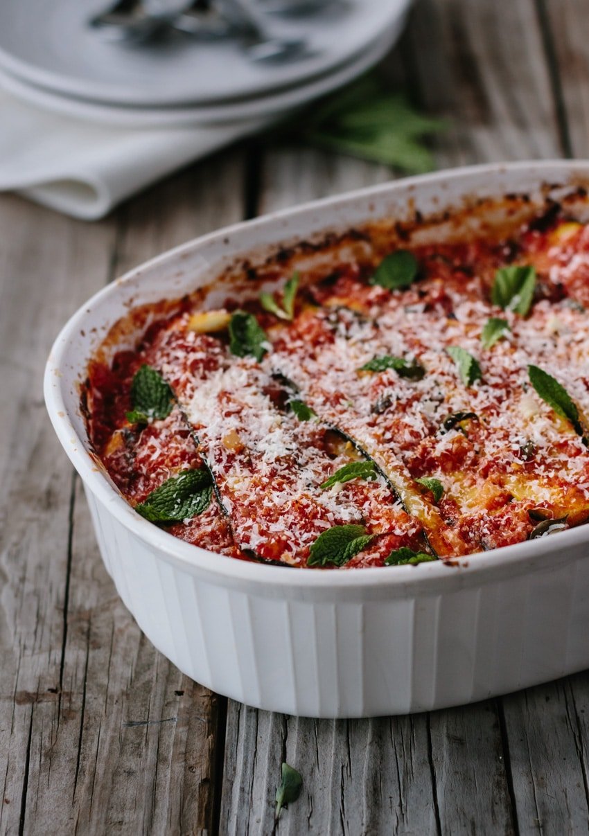 A casserole dish of Zucchini Lasagna garnished with mint and cheese from a close up view from the front.