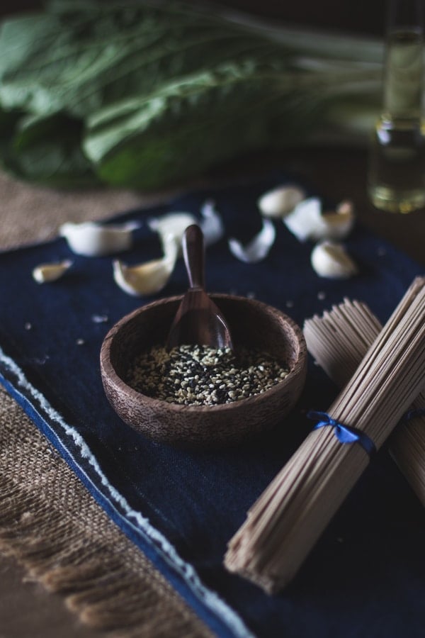 Ingredients for Soba Noodles with Bok Choy on a blue napkin and garlic bulbs in the background