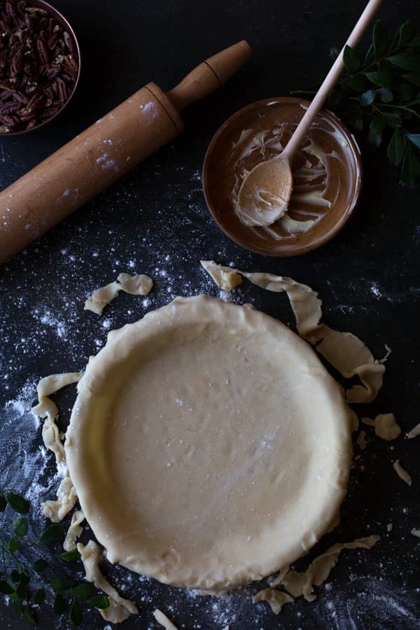 Crust for homemade recipe for Pecan Pie with wooden rolling pen and bowl and spoon