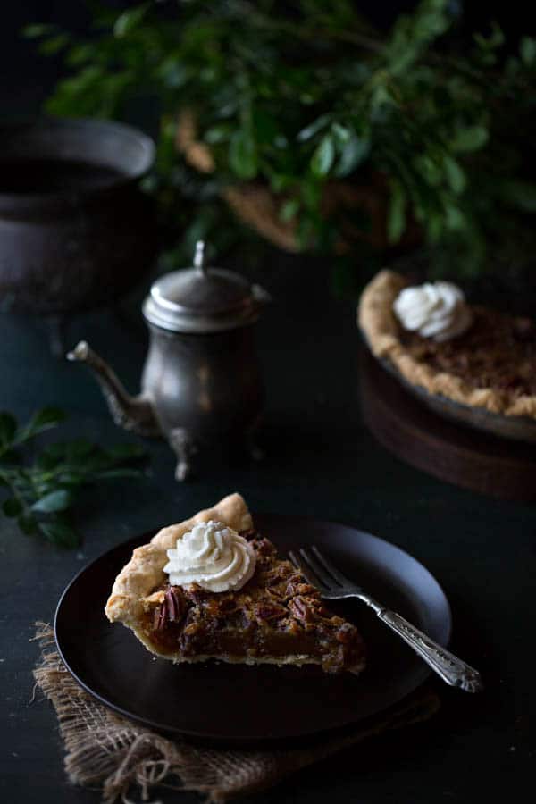 A single slice of Old-Fashioned Maple Pecan Pie with Bourbon Whipped Cream