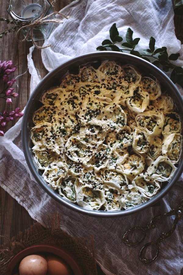 Top view of prepped uncooked Cheesy Parsley Phyllo Rolls in a pan on a napkin