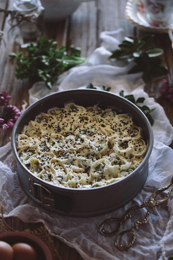 Pan of prepped uncooked Cheesy Parsley Phyllo Rolls on a cloth napkin on a table