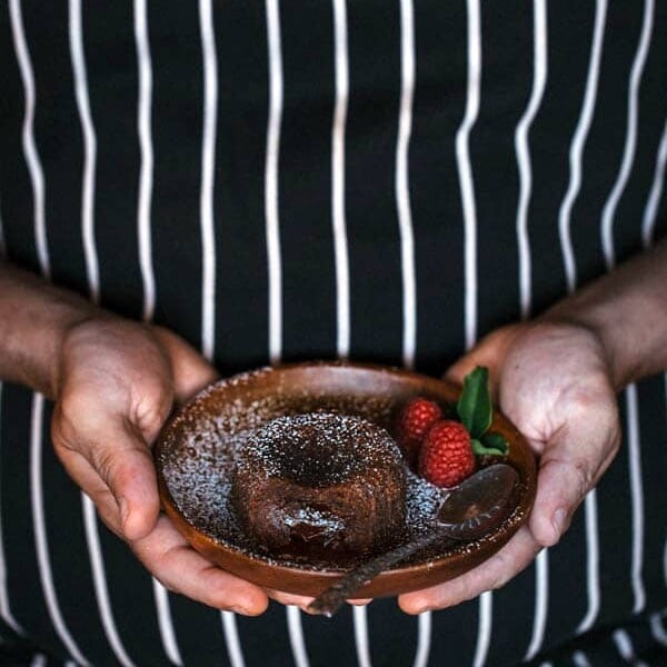 Person in a black and white apron holding Miguel's Chocolate Fondant