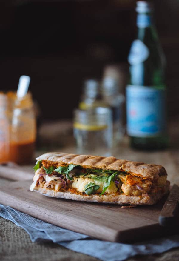 Cauliflower Steak Sandwich with Romesco Sauce with glass of water or bottle of sparkling