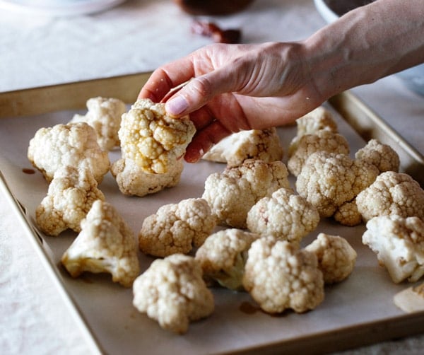 Person placing Cauliflower flowerets placed on sheet pan