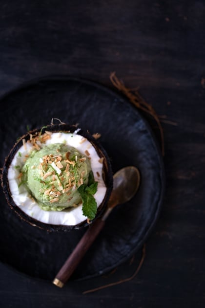 Avocado Coconut Milk Ice cream in a coconut halve with a spoon on the side