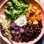 sweet potato quinoa bowl with black beans and tahini dressing placed in a bowl