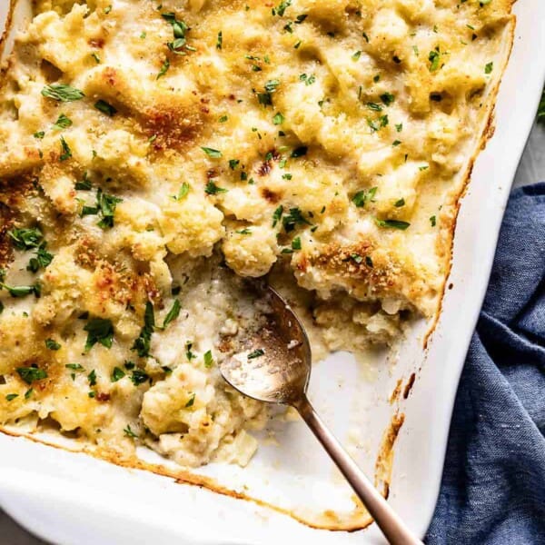 Cauliflower au gratin in a casserole dish with a spoon on the side.