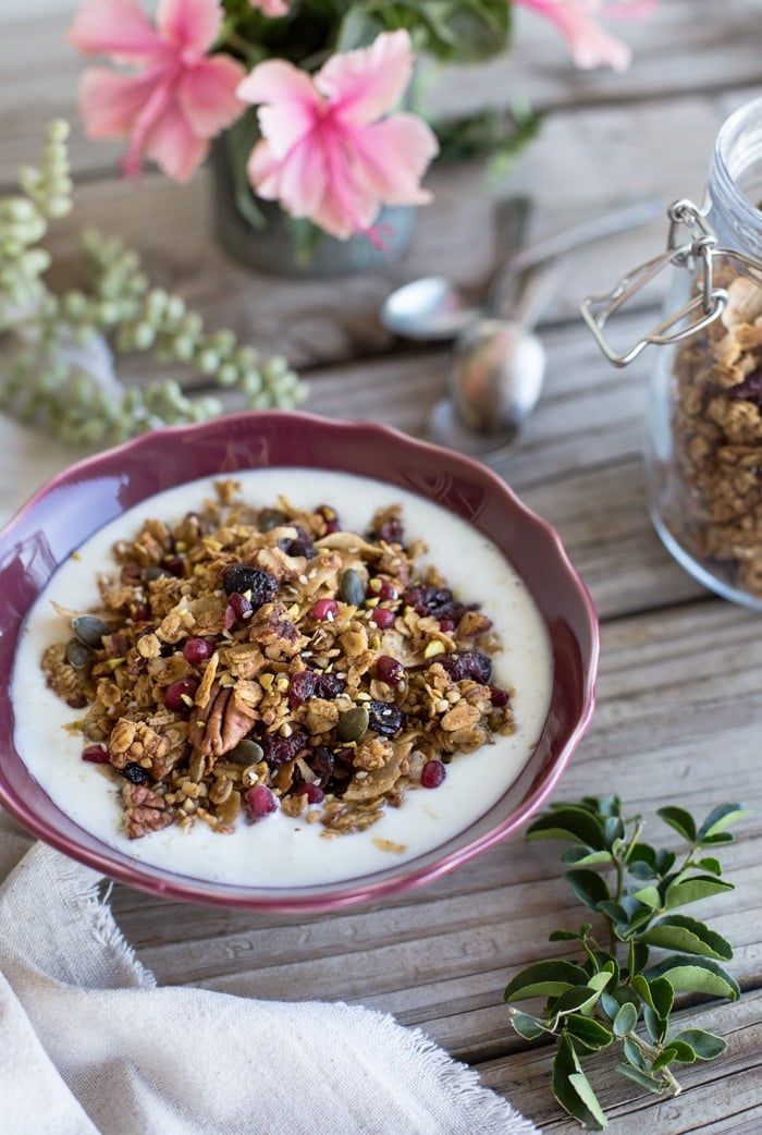 A bowl of Tahini Granola with milk with leaves on the side