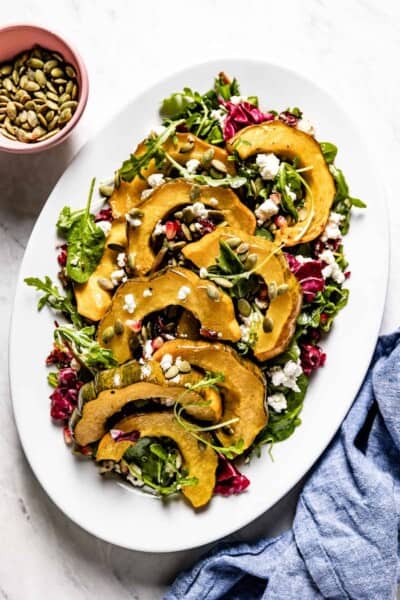 Roasted Acorn Squash Salad with Spicy Pepitas and Cranberries on an oval plate from the top view.