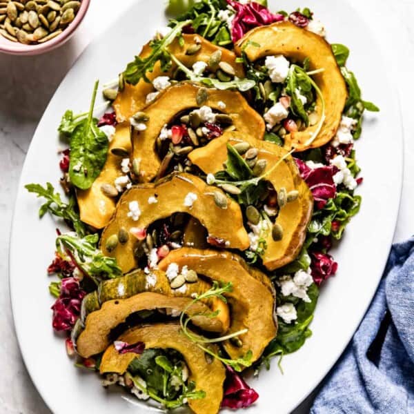 Roasted Acorn Squash Salad with Spicy Pepitas and Cranberries on an oval plate from the top view.