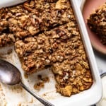 Apple cinnamon baked oatmeal in a square dish with a spoon on the side.