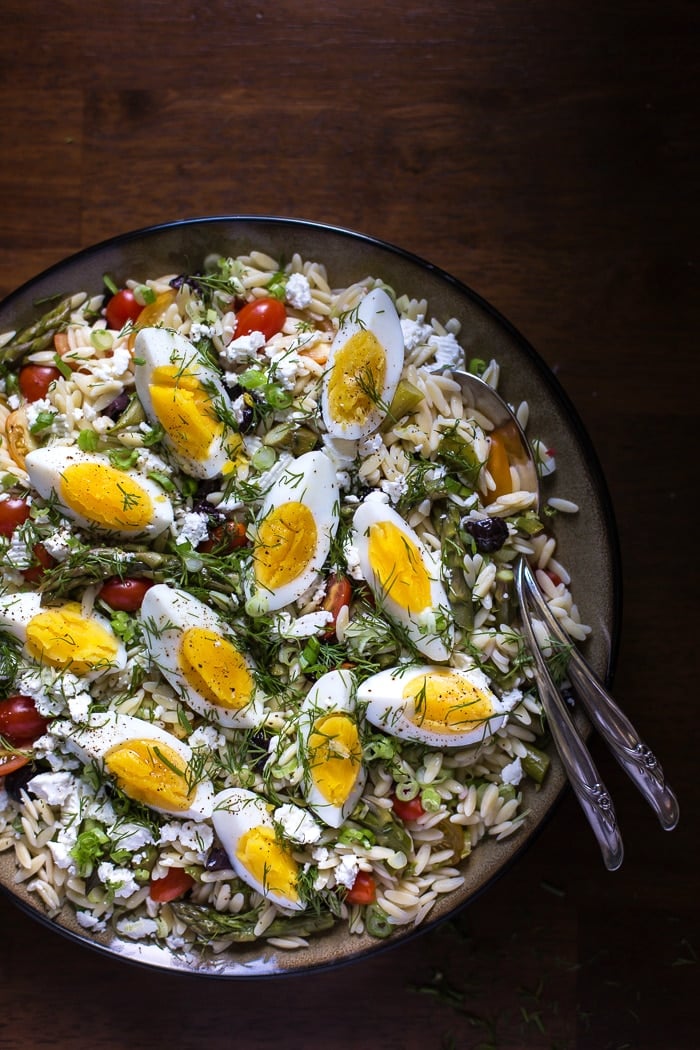 Mediterranean-Style Orzo Salad with Spring Vegetables in a bowl with flatware on the side