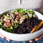 A bowl of Asian Asian Sesame Crusted Seared Tuna Salad is served in a bowl by a woman
