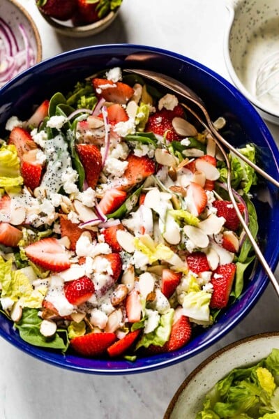 Strawberry Spinach Salad with Poppy seed dressing in a bowl with two spoons on the side