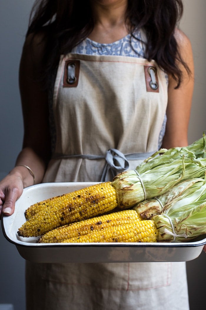 Freshly grilled corn in the hands of a woman