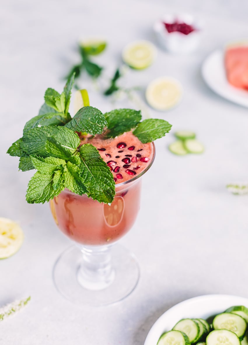 A cup of Cucumber Watermelon Smoothie garnished with pomegranate seeds and mint