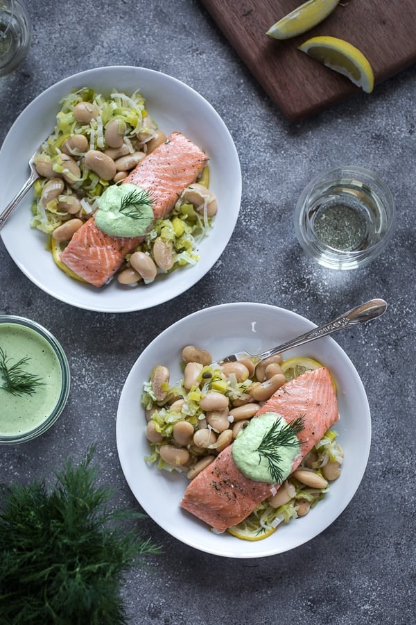Overhead view of two plated seafood dinners of Slow-Baked Salmon with Butter Beans