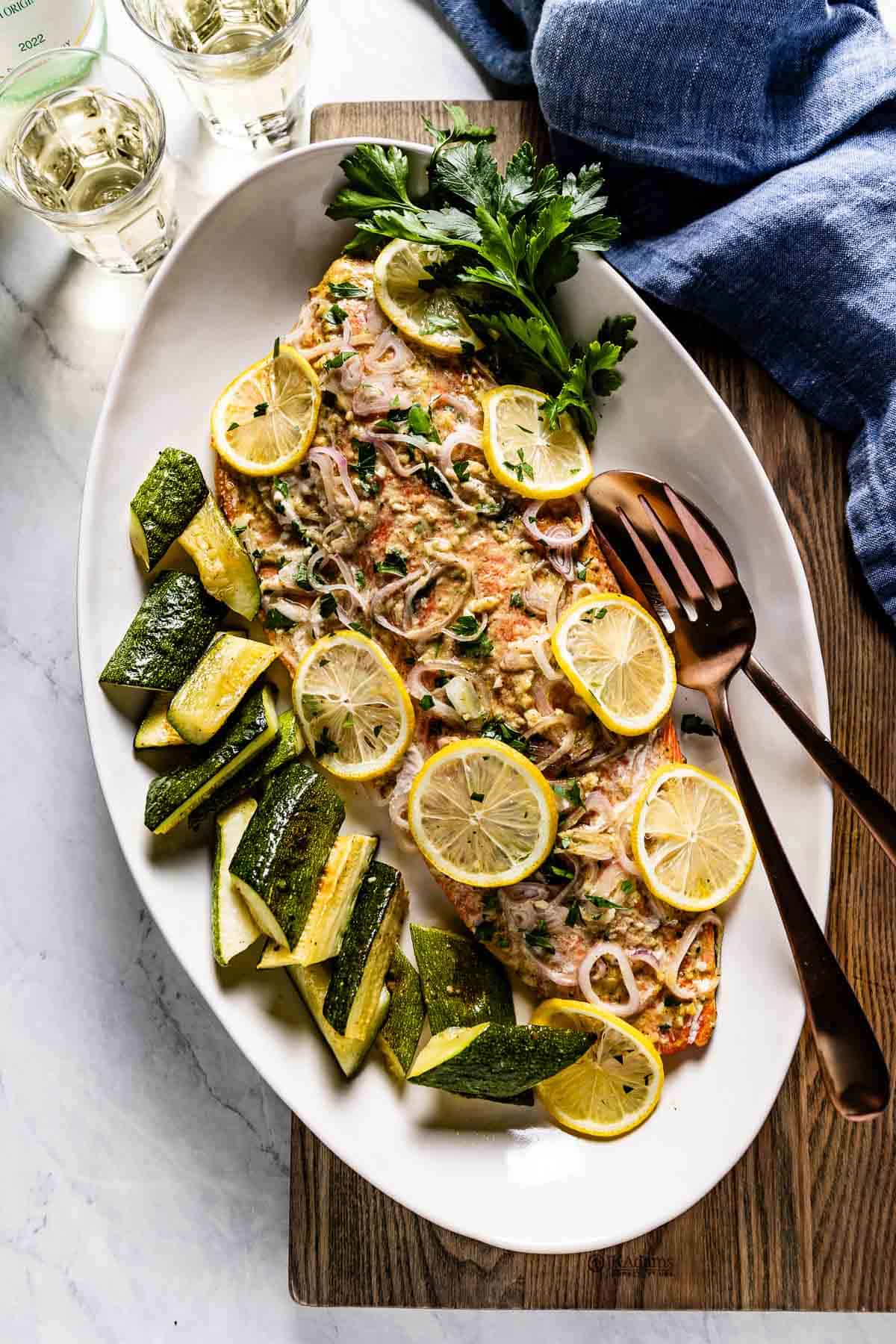 Slow baked salmon garnished with lemon slices and served on an oval plate.