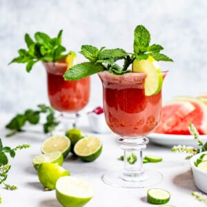 Two glasses of watermelon cucumber smoothie garnished with and lime from the front view.