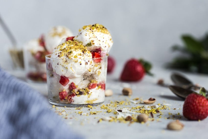 Cashew based ice cream balls in a glass sprinkled with pistachios.