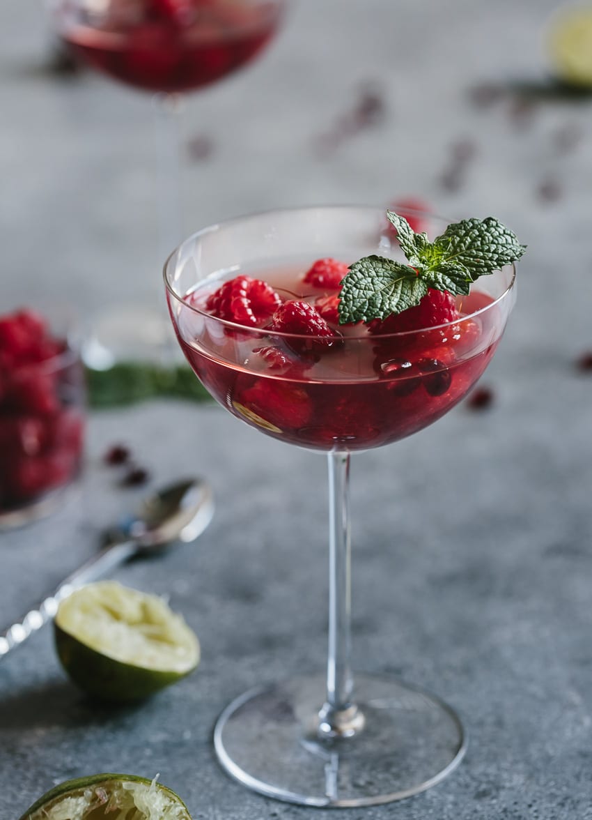 A glass of Raspberry and Pomegranate Rosé Summer Cocktail garnished with mint