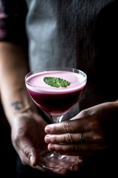 Person holding a glass of Blueberry, Dark Cherry and Calvados Cocktail