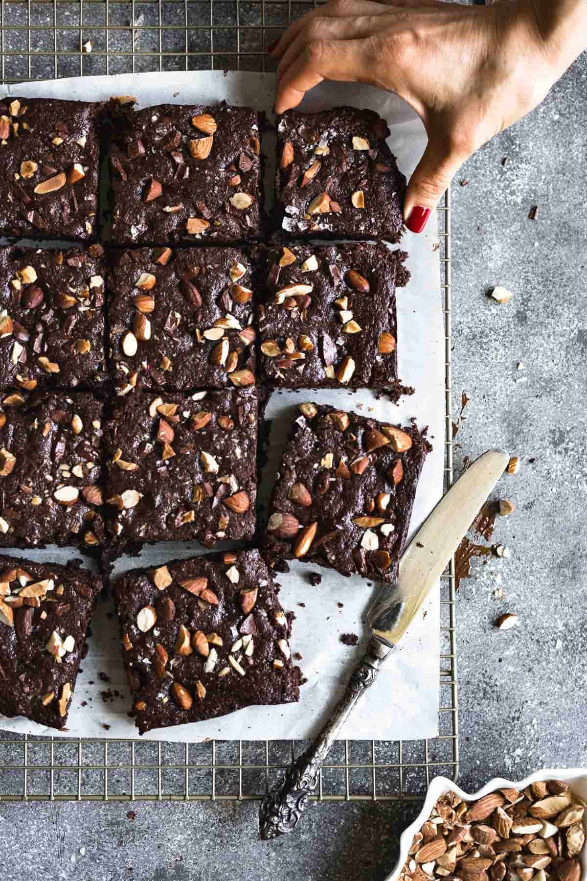 Person taking a slice of spelt flour almond butter brownies from the top view.