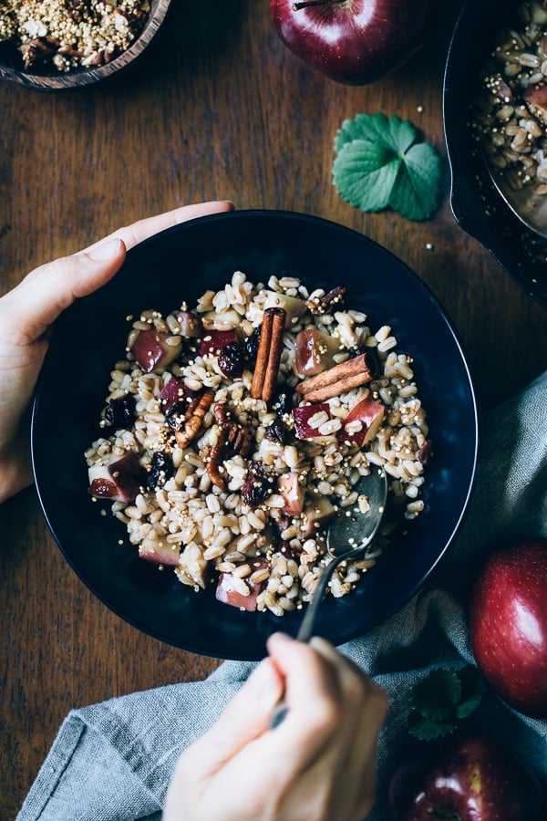 a woman is enjoying a bowl of cooked farro breakfast