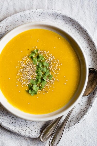 Roasted Kabocha Squash Soup with Sesame Seeds served in a bowl with two spoons on the side