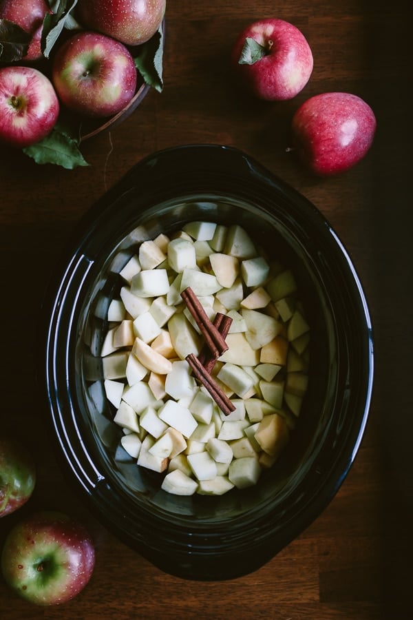 Apples and cinnamon are in a crockpot bowl