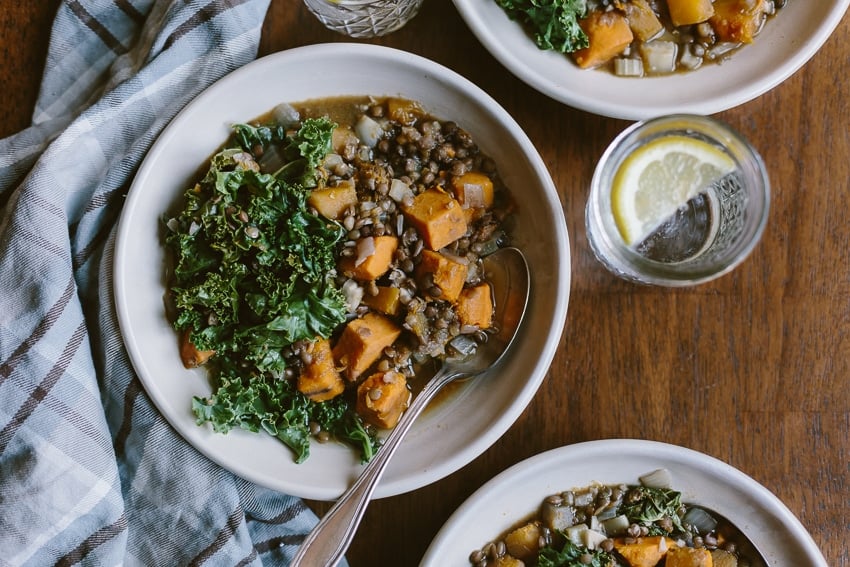 Three bowls of slow cooker butternut squash stew with lemon water on the side