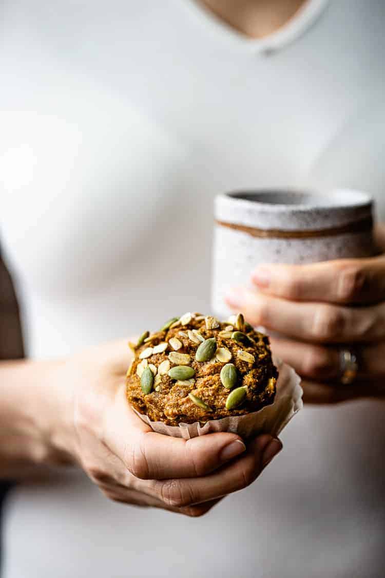 A woman is holding a oatmeal pumpkin muffin in her hand