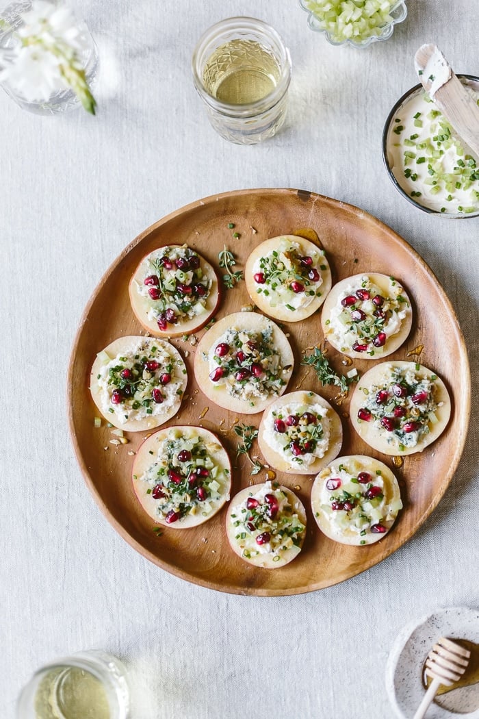 Apple appetizers with cheese, nuts, pomegranate seeds, and celery photographed from the top view