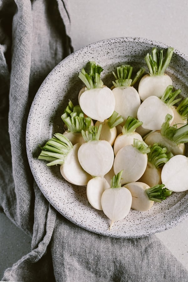 a big bowl of asian turnips are cut into half