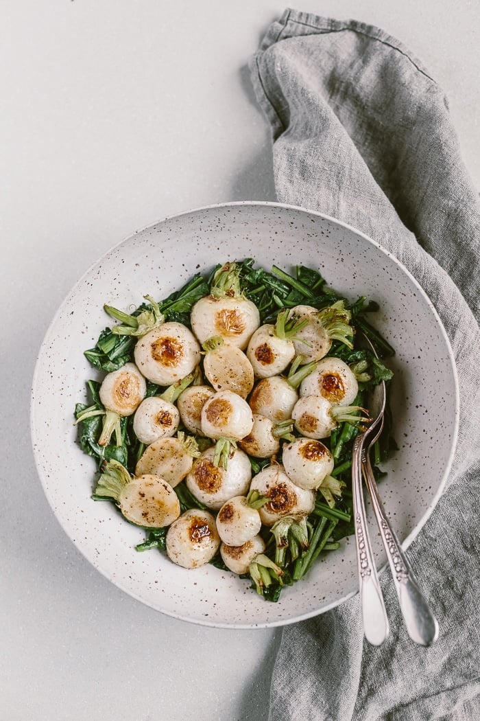 a big bowl of japanese turnips placed on top of sauteed Tokyo turnip greens.