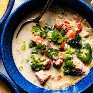 Salmon and coconut soup in a bowl garnished with cilantro.