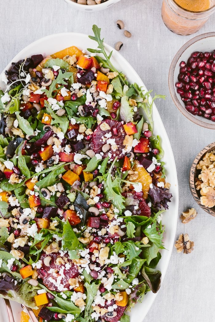 A big bowl of Citrusy Roasted Beet Goat Cheese salad with walnuts and black eyed peas is photographed from the top view.