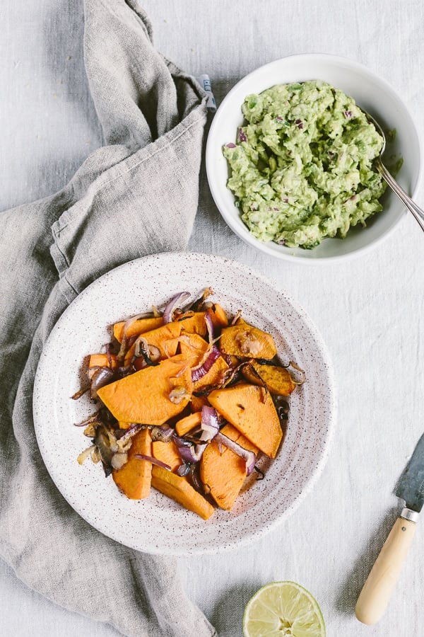 healthy sides for burger consisting of a bowl of cooked sweet potatoes and roasted red onions and a bowl of guacamole