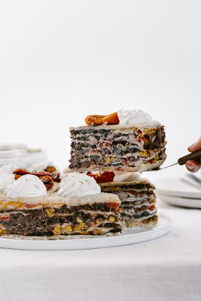 Chicken Quesadilla Cake with a single serving removed and raised: Layers and layers of Mexican flavors stacked up in a 9-inch cake and topped off with sweet peppers and sour cream.